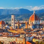 romantic things to do in florence - iconic image looking over the Italian city of Florence. the orange topped Duomo is visible and mountains in the distance