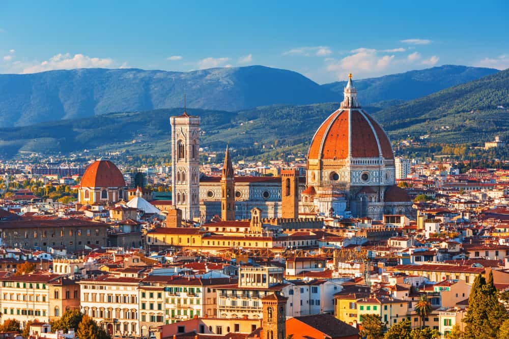 romantic things to do in florence - iconic image looking over the Italian city of Florence. the orange topped Duomo is visible and mountains in the distance
