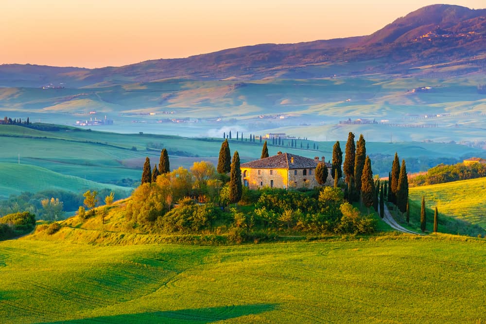 stunning landscape of tuscany - classic italian home surrounded by trees with hills in thre distance - romantic things to do in tuscany